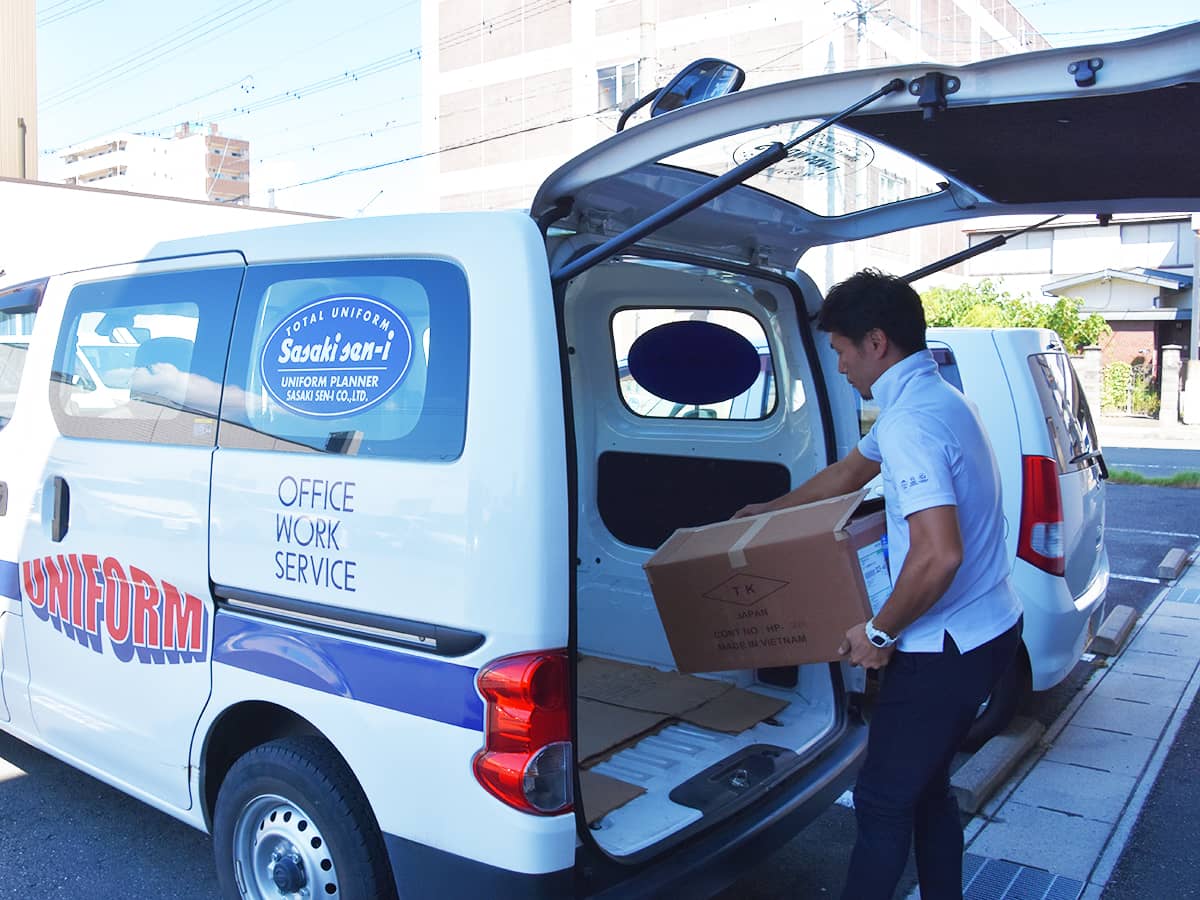 ユニフォームを社用車に積み込む社員