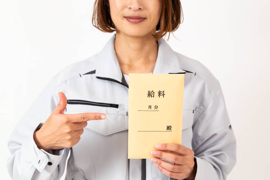 中小企業の昇給平均白背景に給料袋を持つ作業服の女性
